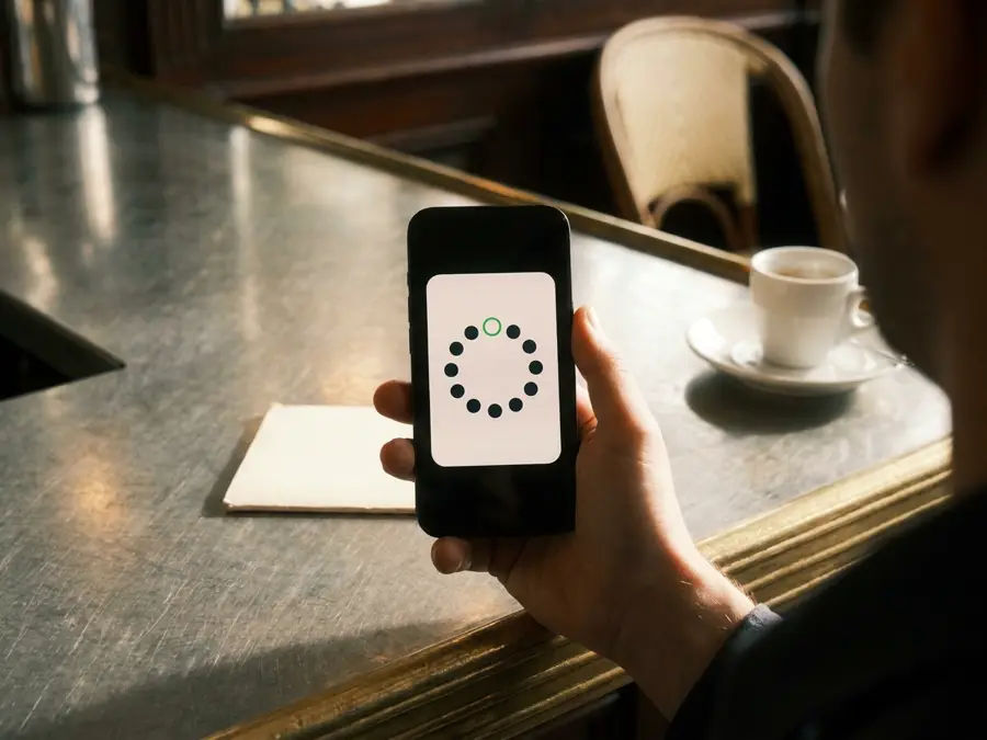 Un téléphone tenu au-dessus du comptoir affiche une carte de fidélité qui vient d'être ajoutée au wallet.